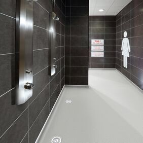 Grey coloured safety flooring in a public ladies shower area 