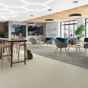 Light stone effect safety flooring alongside silver oak effect safety flooring in a communal break area in a education setting