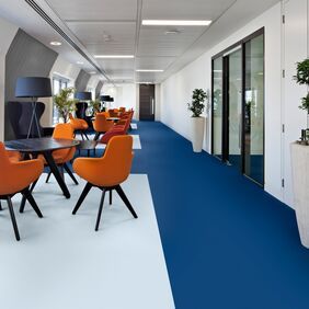 Office seating areas with blue flooring and orange chairs