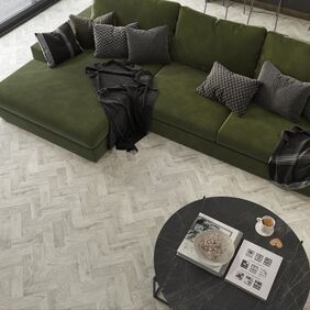 Overhead photo of light grey parquet flooring and a dark green couch