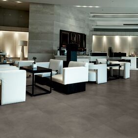 Resturant dining area with stylish white chairs featuring dark concrete effect flooring 