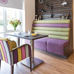 Brown oak wood effect flooring in a Aged/residential care communal dining area with colourful seating