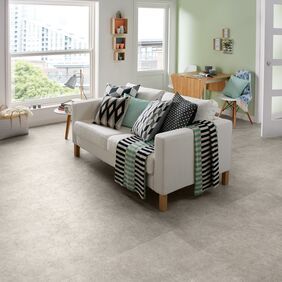 Living room space with sofa, table and chairs featuring a stone effect flooring in Burnished Concrete straight laid 