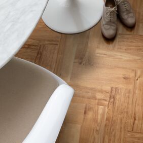 Close up of a white stool sat on Nut tree oak colour Herringbone design laid flooring 