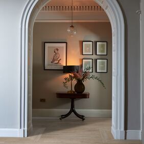 Hallway, arched door frame, lights, table, plant, wood floor 