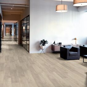 Oak effect flooring in a long corridor with a seating area and black leather chairs