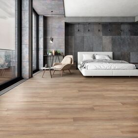 Wood effect flooring lad in a large bedroom with a white bed and chair