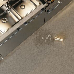Overhead shot of a commercial kitchen with a spilled drink on the dark coloured floor