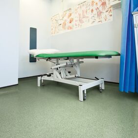 Hospital room with a bed and green coloured flooring