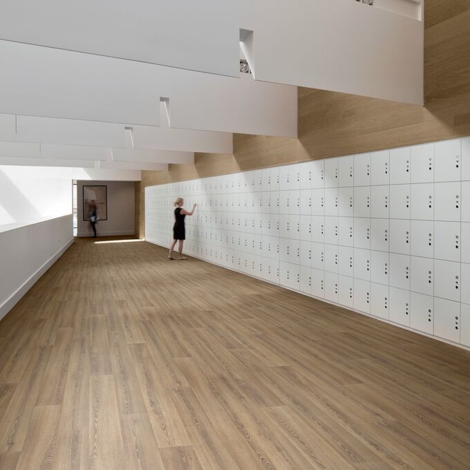 Roasted limed ash wood effect flooring in a education corridor with white storage lockers