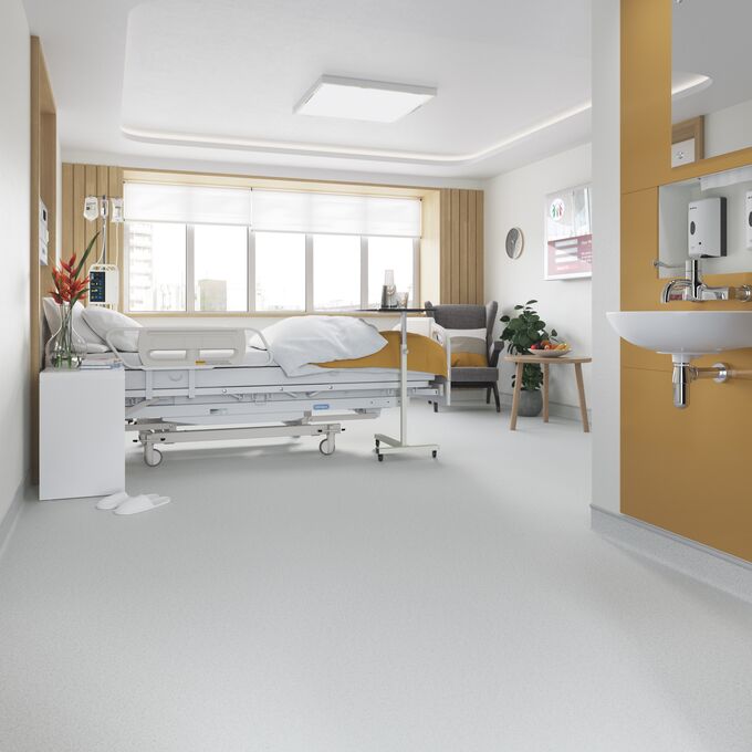 Light grey safety flooring in a hospital room with bed and sink area 