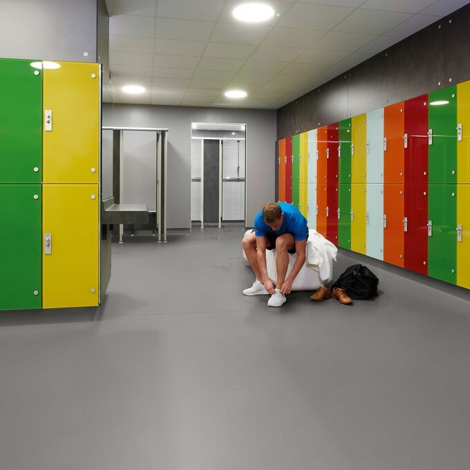 Grey colour safety flooring in a changing room with multi coloured lockers 
