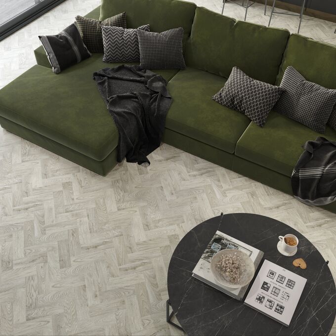 Overhead photo of light grey parquet flooring and a dark green couch