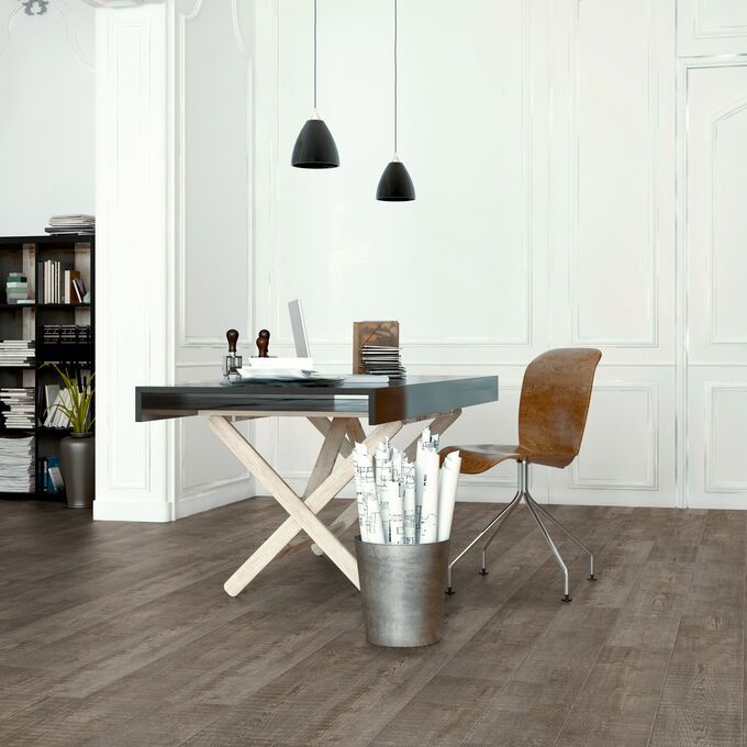 Dark coloured wood effect flooring in an open office room with a single desk