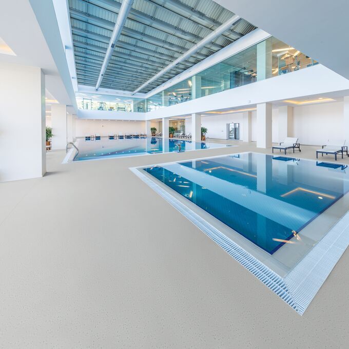Neutral coloured safety flooring around a swimming pool area 